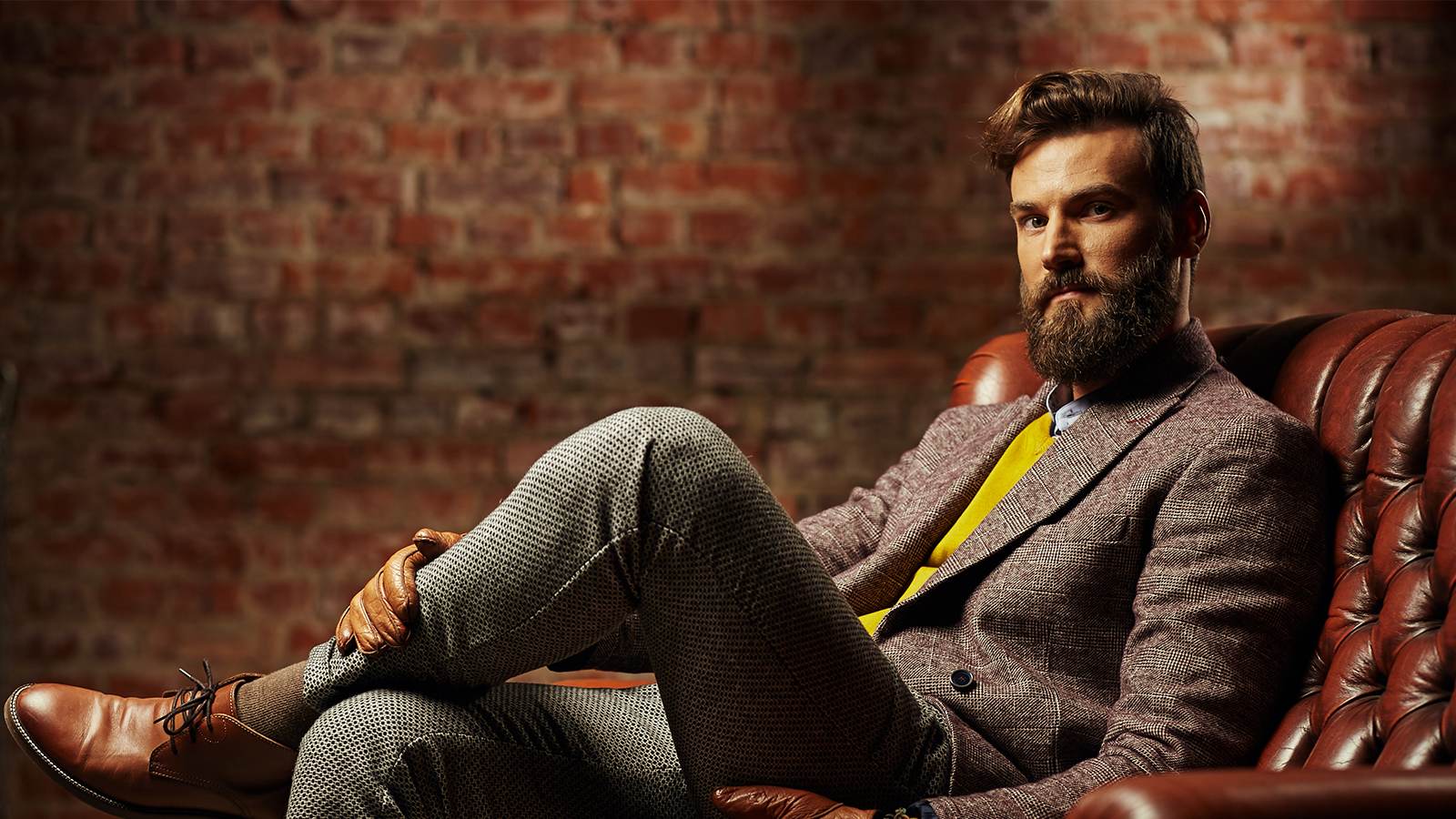 Homem bem-vestido de perfil corporativo sentado numa poltrona de couro